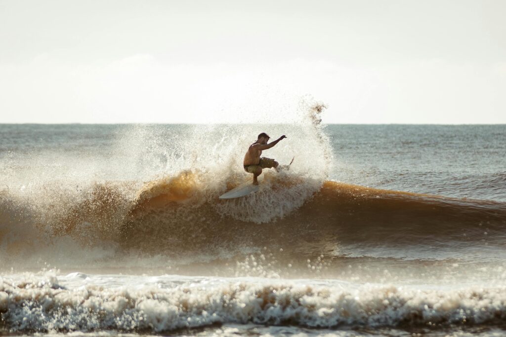 Surfista descendo uma onda em preto e branco, ilustrando o guia de equipamentos de surf para iniciantes
