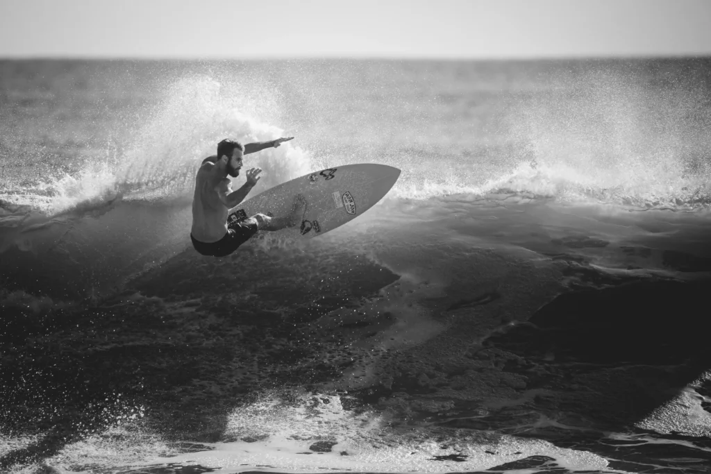 Surfista avancado fazendo uma manobra radical em pranchinha menor, com respingo de agua