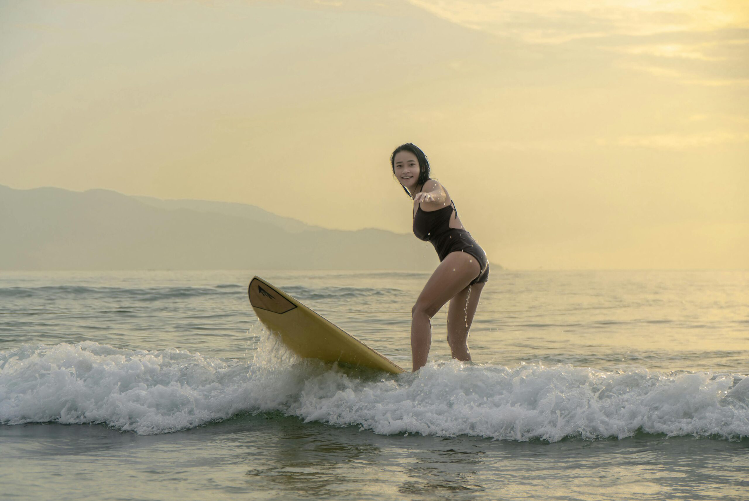 Iniciante praticando pop-up em um longboard amarelo na espuma da onda