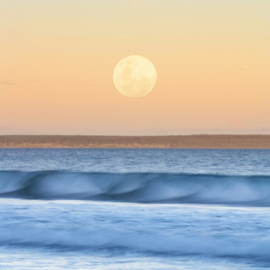Lua cheia surgindo sobre o mar ao entardecer